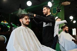 Handsome bearded man at the barbershop, barber at work. photo