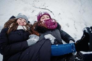 Two funny girls friends having fun at winter snowy day near snow covered trees. photo