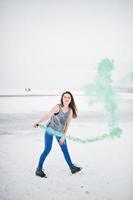 Young girl with green colored smoke bomb in hand in winter day. photo