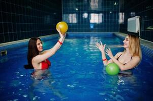 Two sexy girls in swimsuit having rest in sauna swimming pool, playing ball. photo