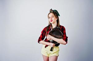 Young funny housewife in checkered shirt and yellow shorts pin up style with frying pan isolated on white background. photo