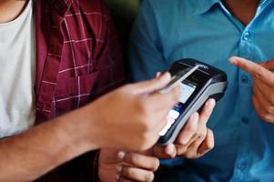 Two customers are paying using contactless credit card and payment terminal. photo