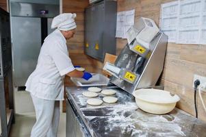 Female chef preparing pizza in restaurant kitchen. photo