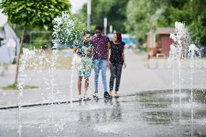 Three african american friends walking on fountains. Having fun together. photo