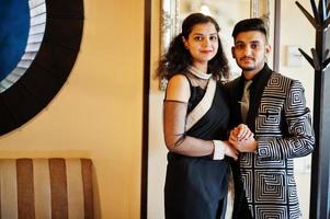 Lovely indian couple in love, wear at saree and elegant suit, posed on restaurant. photo