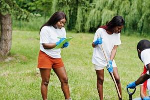 Group of happy african volunteers planting tree in park. Africa volunteering, charity, people and ecology concept. photo