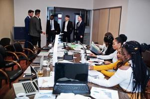 Multiracial business team addressing meeting around boardroom table. photo