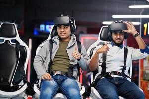 dos jóvenes indios divirtiéndose con una nueva tecnología de auriculares vr en un simulador de realidad virtual. ellos felices y muestran el pulgar hacia arriba. foto