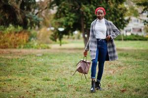 Young modern fashionable, attractive, tall and slim african muslim woman in hijab or turban head scarf and coat posed at park. photo