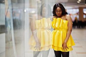 elegante mujer afroamericana en vestido amarillo posó en el centro comercial. foto