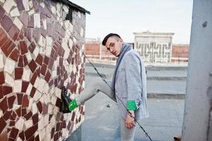 Dreamer stylish macho man in gray suit, scarf and glasses posed on the roof. photo