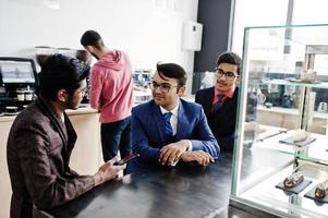 Group of three indian businessman in suits sitting on cafe. photo