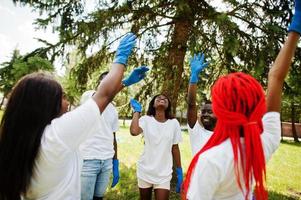 Group of happy african volunteers put hands in hands in park. Africa volunteering, charity, people and ecology concept. photo