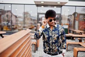 Attractive and handsome stylish indian man wear on shirt and sunglasses standing in the terrace of modern lounge cafe at his work break. photo