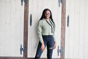 City portrait of positive young dark skinned female wearing green hoody and eyeglasses. photo