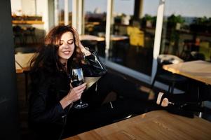 joven mujer rizada disfrutando de su vino en un bar. foto