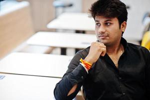 Stylish indian man sitting at fast food cafe and waiting his order. photo