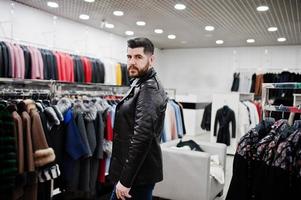 Stylish turkish man at the store of fur coats and leather jackets. Successful arabian beard man. photo