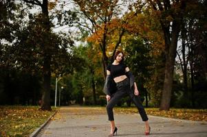 A tall leggy young beautiful and elegant model woman at formal wear posed at autumn background. photo