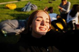 Young multi ethnic group of people watching movie at poof in open air cinema. Close up portrait of funny girl. photo