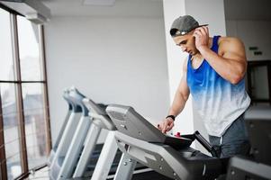 Fit and muscular arabian man running on treadmill in gym. photo