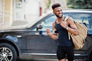 African american male athlete sport man with backpack against his black suv car before training. photo