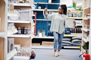 African woman choosing clock for her apartment in a modern home furnishings store. photo