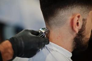 apuesto hombre barbudo en la barbería, peluquero en el trabajo. cerrar la nuca. foto