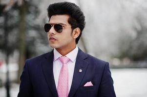 Elegant indian macho man model on suit and pink tie, sunglasses posed on winter day. photo