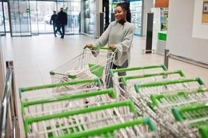 African woman with shopping cart trolley posed indoor market. photo