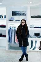 hermosa chica morena en la boutique de la tienda de ropa en la chaqueta de invierno. foto