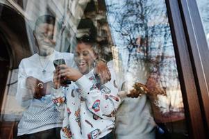 Happy african friends chatting in cafe. Group of black peoples meeting in restaurant against glass of window. photo