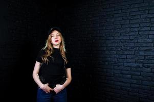 FBI female agent in cap and with gun at studio against dark brick wall. photo