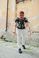 Lifestyle portrait of handsome man posing in the city in the old courtyard. photo