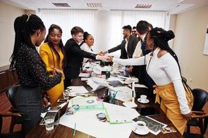 buen negocio. equipo de negocios multirracial que se dirige a la reunión alrededor de la mesa de juntas y se da la mano. foto