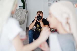 Man photographer shooting on studio two girls while they make their own masks cream. Professional photographer on work. photo