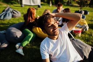 Young multi ethnic group of people watching movie at poof in open air cinema. Close up portrait of funny guy. photo