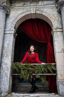 Brunette plus size model at red against arch with curtains. photo