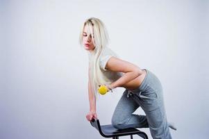 Blonde sporty girl with yellow dumbbell posed at studio against white background. photo