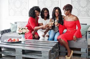 Group of partying african girls clinking glasses with sparkling wine champagne. photo