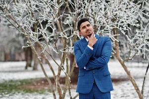 elegante modelo de hombre de moda indio en traje posado en el día de invierno y pensando. foto