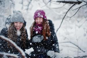 dos amigas divertidas divirtiéndose en el día de invierno cubierto de nieve cerca de árboles cubiertos de nieve. foto