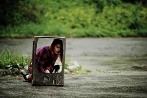 Fashion portrait of redhaired sexy girl outdoor. Model attractive dramatic woman with old tv box. photo