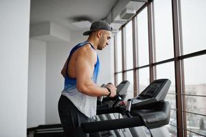 Fit and muscular arabian man running on treadmill in gym. photo