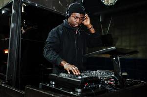 dj afroamericano toca música en cubiertas en el club nocturno. foto