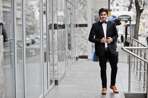 joven indio con traje negro y pajarita posó al aire libre. foto