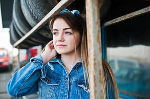 joven hipster con chaqueta de jeans y pañuelo en la cabeza en la zona de montaje de neumáticos. foto