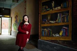 Brunette plus size model against wall like library. photo