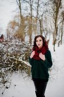 Brunette girl in green sweater and red scarf outdoor on evening winter day. photo