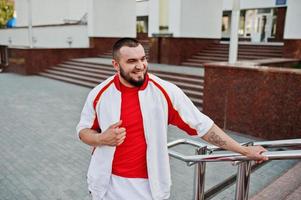 Young brutal bearded muscular man wear on white sport suit with red shirt. photo
